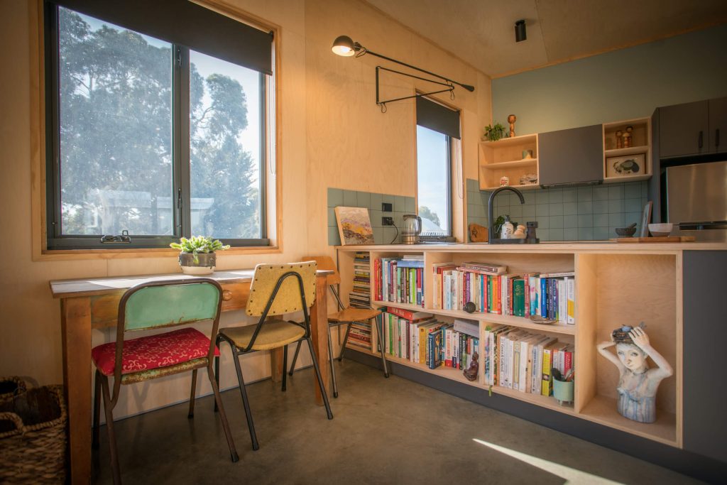 Cosy kitchen with bookshelves, table and chairs.