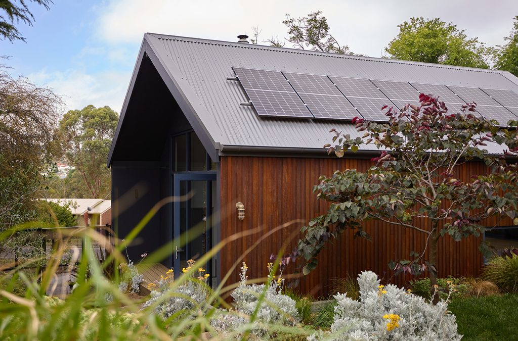 Eco-friendly house with solar panels, garden view.